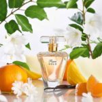 Rare Gold Perfume surrounded by citrus fruits and lilies